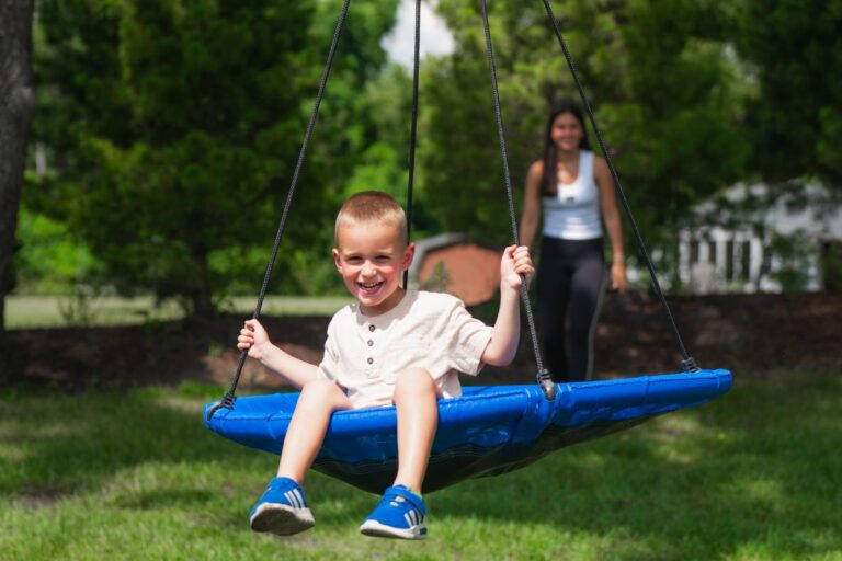 Smiling boy on a saucer swing with his sitter